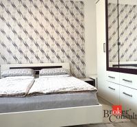 A bedroom in a 3-room apartment with a bed and a wardrobe, patterned wallpaper on the wall.