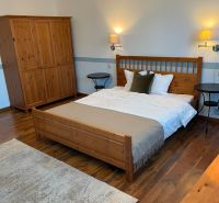 A bedroom with wooden furniture, a floor with a wooden decor, and a carpet in a family house.