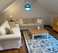 Attic room in a family house with sofas, a carpet, and a wooden decor floor.