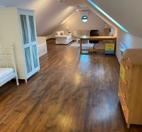 Attic room with wooden decor, sofa, table, and bed in a family house.