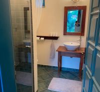 A bathroom with a sink on a wooden table and a shower corner.
