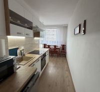 A kitchen in a 2-room apartment with a wooden decor floor and a dining table.