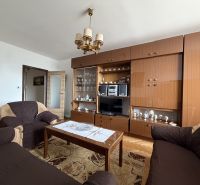Living room in a two-room apartment with wooden decor furniture and a chandelier.