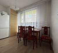 Dining area in a 2-room apartment with wood-patterned flooring and a white refrigerator.