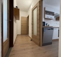 Hallway of a 2-room apartment with a kitchen, white walls, and a floor with a wooden decor.