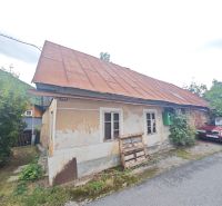 A family house in Špania Dolina with visible plaster and a metal roof.