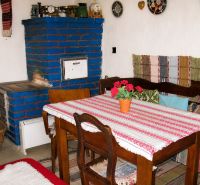 A traditional cottage with a blue stove and wooden furniture, colorful textiles.
