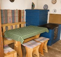 Corner bench with table, blue stove, decorative plates on the wall.