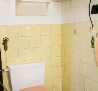 A bathroom in a cottage with beige tiles and shelves for necessities.