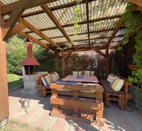 A cottage in Beňadiková with a covered terrace, outdoor seating, and a fireplace under a wooden pergola.