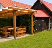 Wooden cottage in Beňadiková with garden seating and a grill on the green grass.