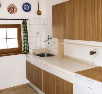 A kitchen in a cottage with wooden decor and colorful dishes on the wall.