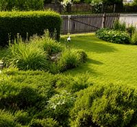 A garden by the cottage in Beňadiková with a lawn, ornamental shrubs, and flowers.