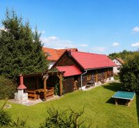 A wooden cottage in Beňadiková with a terrace and a garden table on a grassy area.