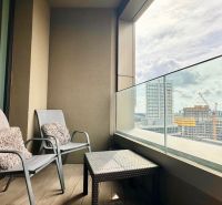 A balcony of a 2-room apartment with two chairs and a view of the city.