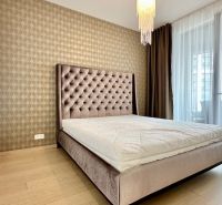 A bedroom with a bed, curtains, wallpaper, and a wooden decor floor in a 2-room apartment.