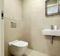 A toilet with a simple sink and mirror in a 2-room apartment.
