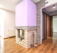 Interior of a family house with a fireplace, purple walls, and a wood-patterned floor.