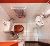 Bathroom in a family house with tiles, a toilet, and a small sink.