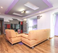 Living room with an orange sofa, television, and wooden decor flooring in a family house.