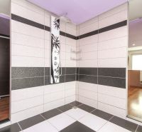 A shower corner with modern tiles and a wooden decor floor in a family house.