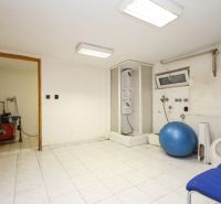 A bathroom in a family house with a shower, an exercise ball, shelves, and tiles.