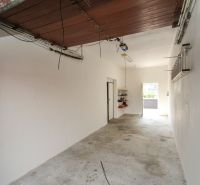 The interior of a garage in a family house with open doors and practical shelves.