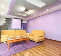 Living room with purple walls and a brown sofa in a family house.