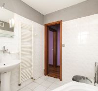 A bathroom in a family house with a sink, a bathtub, and white tiles.