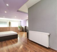 A bedroom in a family house with a purple ceiling and a wooden decor floor.