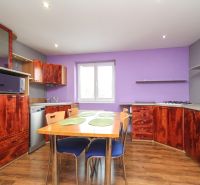 A kitchen in a family house with dark wood furniture and a floor with a wooden decor.