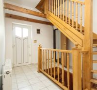 A staircase with a wooden railing and white tiles in a family house.