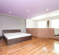 A bedroom in a family house with a wooden decor floor and a purple ceiling.