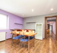 Dining area with chairs and a refrigerator in a family house, floor with wooden decor.