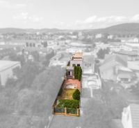 A family house on Kubranská Street in Trenčín, with a plot of land, a hedge, and trees.
