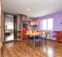A kitchen in a family house with a wooden decor floor, wooden furniture, and a purple wall.
