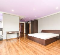 Bedroom with a bed, built-in wardrobe, and wooden decor flooring in a family house.