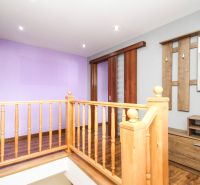 A hallway in a family house with wooden railing and flooring with a wooden decor.