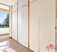 A built-in wardrobe next to the balcony in a 2-room apartment with a view of greenery.
