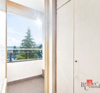 A balcony in a 2-room apartment with a view of greenery and a sunny horizon.