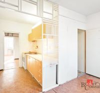 A kitchen in a 2-room apartment with a wooden decor floor and white walls.