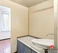 Bathroom with a bathtub and a sink in a 2-room apartment, without visible tiles.