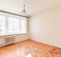 A room in a 2-room apartment with a wood-patterned floor and a large window.