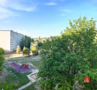 A view of a children's playground and apartment buildings amidst greenery on A. Hlinka Street, Zvolen.