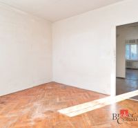 An empty room with white walls and a floor with a wooden decor in a 2-room apartment.