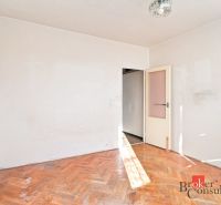 An empty room with wood-patterned flooring in a two-room apartment, neutral interior.
