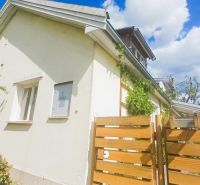 A family house in Rožňava with a fence and greenery, clear sky in the background.