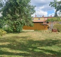 A garden of a family house in Rožňava with a lawn, trees, and a wooden gazebo.