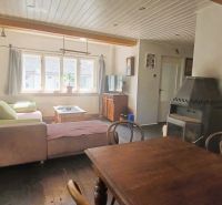 Living room of a family house with a wooden table and a fireplace, floor with wooden decor.