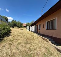A cottage in Dubové with a garden and surrounding nature on a slope, blue sky.